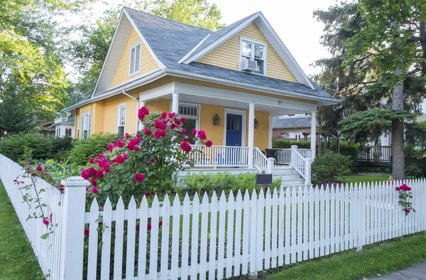 Gelbes Haus mit rosa Rosenstrauch davor Stockfoto