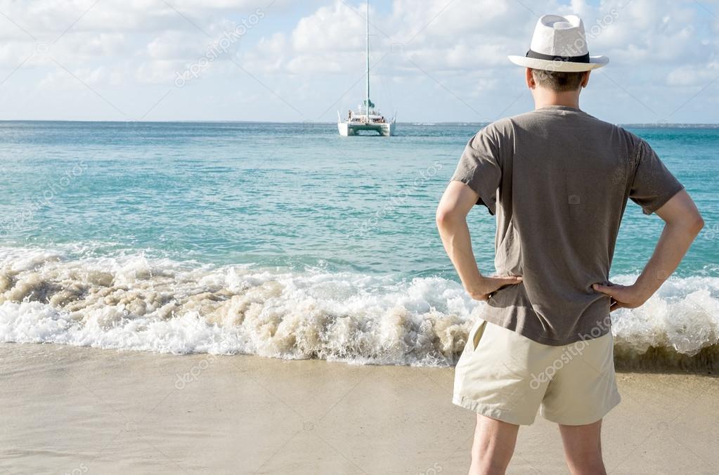 Back View of a Man in White Hat Standing on a Beach