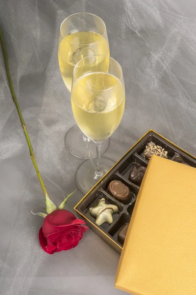Dos copas de champán, una rosa roja y una caja abierta de chocolates gourmet —  Fotos de Stock