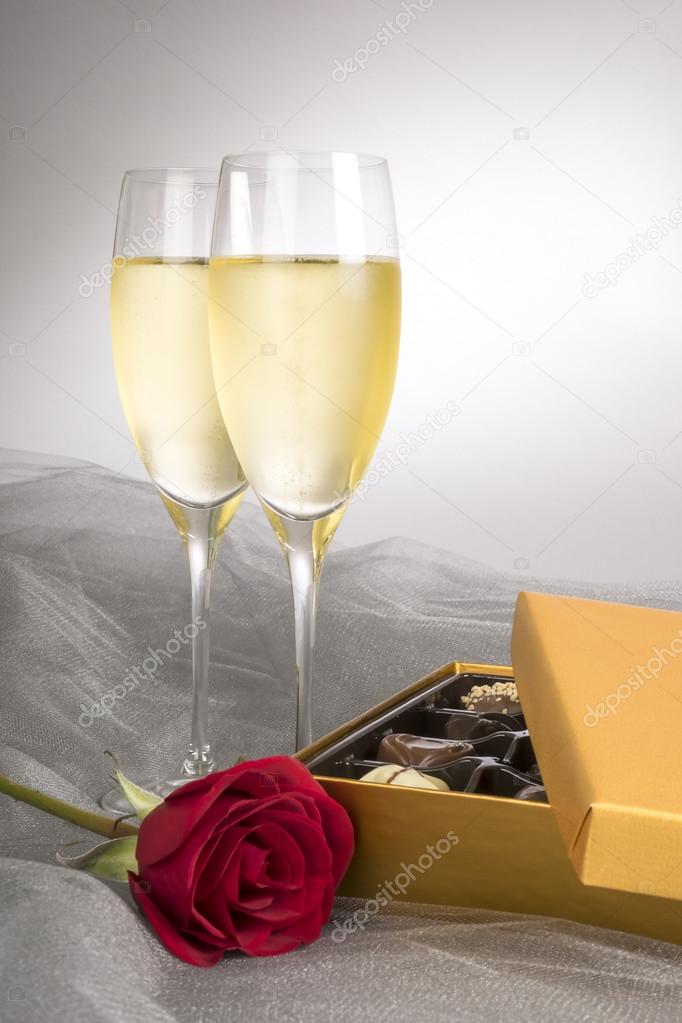 Two Glasses of Champagne with One Single Red Rose and Box of Gourmet Chocolates