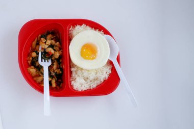 Kırmızı plastik kutuda haşlanmış pirinçli sahanda yumurtalı baharatlı fesleğen tavuğu, tek kullanımlık plastik kaplar. Yemek için hazır.