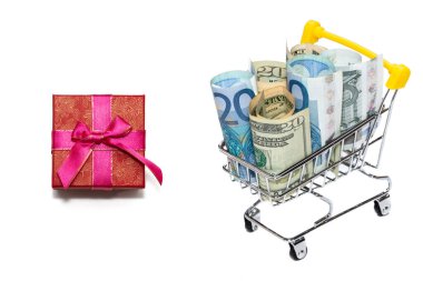 Avro ve dolarlarla dolu bir alışveriş arabasının yanında kırmızı bir hediye kutusu. Sancak boyutu. Beyaz arka planda izole edilmiş. Hediye, tatil alışverişi konseptleri. Boşluğu kopyala.
