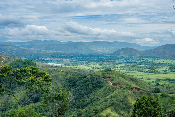 Mogotes Vadisi 'nin geniş manzarası, yemyeşil dağlar, tarım alanları ve uzak bir kasaba.