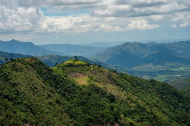 Verdant dağları ve tepeler yoğun orman yapraklarıyla kaplı bulutlu bir gökyüzü altında geniş bir araziye yayılmış, Santander bölgesinin doğal güzelliğini gösteriyor