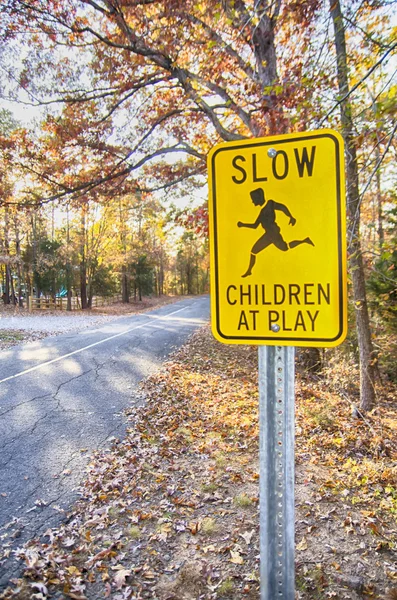 Sarı yavaş altındaki çocuklar oynamak yol işaret ve yol — Stok fotoğraf