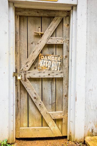 old wooden door with danger sign