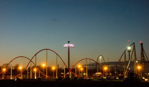 Por do sol sobre um parque de diversões em uma distância — Fotografia de Stock