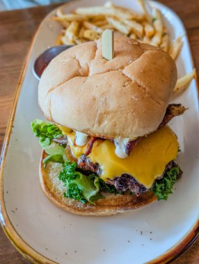 Sığır burger. Biftek burger, domates, peynir, salatalık turşusu ve kırmızı soğanlı sandviç.