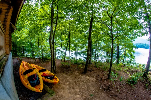 Dos kayaks naranja de pie cerca de la cabaña junto al lago —  Fotos de Stock