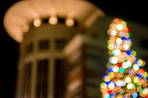 Desenfocado árbol de navidad luces en un fondo de la ciudad — Foto de Stock