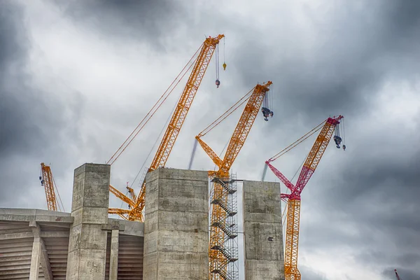 Тяжелые строительные краны, возводящие бетонное здание — стоковое фото