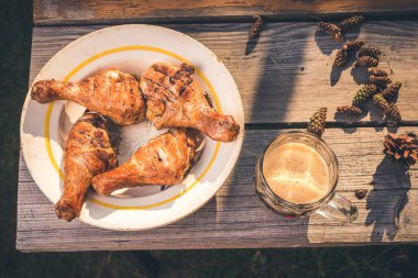 Tabakta kızarmış tavuk bacağı ve ahşap bir masada bir bardak bira tabakta kızarmış tavuk bacağı ve bir bardak bira. Üst görünüm.