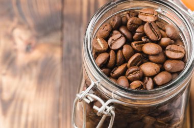 Ahşap bir masada cam bir kavanozda kahve. Üst Manzara. Açık cam bir kavanozdaki kahve tanecikleri ahşap bir masada fotokopi alanı ile.