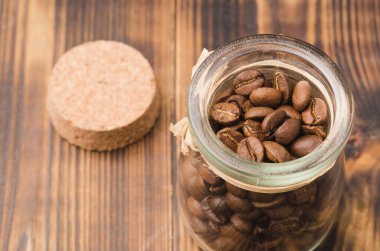 Ahşap bir masada cam bir kavanozda kahve. Üst Manzara. Tahta bir masada açık cam bir kavanozda kahve taneleri..
