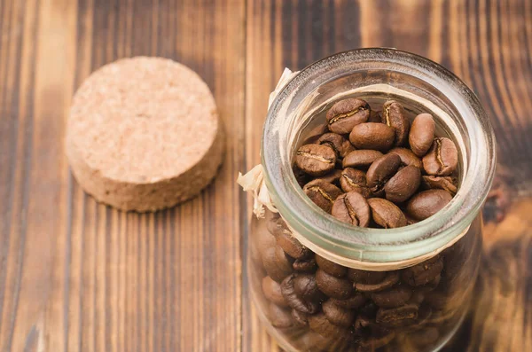 Ahşap bir masada cam bir kavanozda kahve. Üst Manzara. Tahta bir masada açık cam bir kavanozda kahve taneleri..