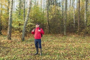 Sırt çantalı genç adam ormanda yürüyor. Seyahat teması. Sırt çantalı genç adam ön tarafta yürüyor.