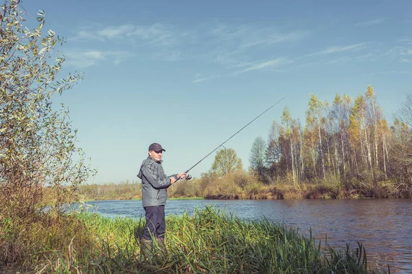 男は釣り竿を持って岸に立っている 晴れた日には 美しい釣り風景 — ストック写真