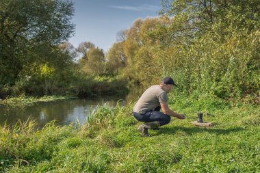 Elinde kupa olan genç bir adam doğada oturuyor. Turizm.