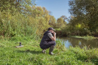 Elinde kupa olan genç bir adam doğada oturuyor. Turizm.