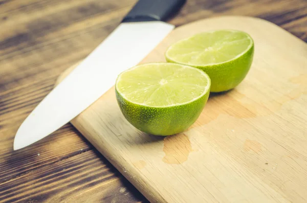 Tahta bir masada bıçakla dilimlenmiş kireç. Yukarıdan görüntüle.