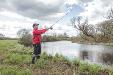 Balıkçı kıyıda bulutların arkasına doğru yakalar. 