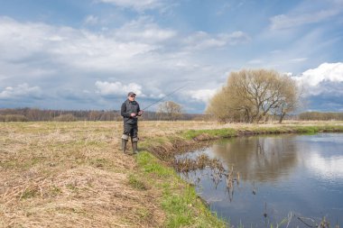 Balıkçılar kıyıya, gökyüzünün arka planına doğru bulutlu bir çubuk fırlatıyor..
