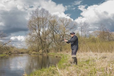 Balıkçılar kıyıya, gökyüzünün arka planına doğru bulutlu bir çubuk fırlatıyor..