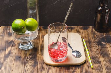 Kırmızı içeceği bardakta buzla karıştırmak. Karanlık bir arka planda kokteyl hazırlıyorum..