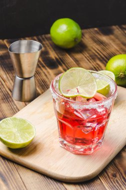 Ahşap bir masada limon ve buzdan kırmızı bir kokteyl hazırlıyorum..