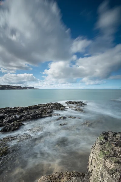 Sziklák és Penmon pont, Anglesey kavargó dagály. — Stock Fotó