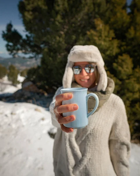 A woman holding a mug of coffee on the winter background