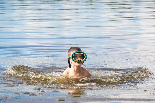 Boy in river water with scuba mask on summer day