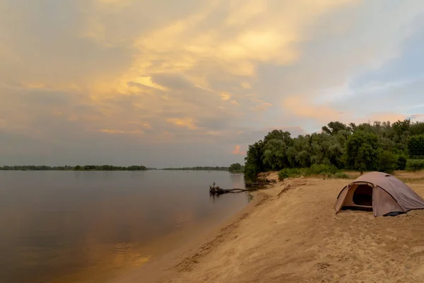Turistický stan na vysokém břehu řeky při západu slunce. Krásná letní krajina — Stock fotografie