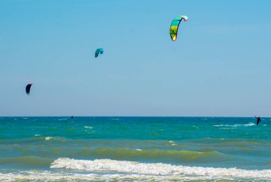 Üç uçurtmacı denizde sörf yapıyor.