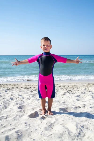 Kleiner Junge im Taucheranzug lächelt am Strand — Stockfoto