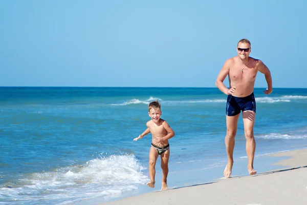 Lycklig far och hans lite sun kör på stranden — Stockfoto