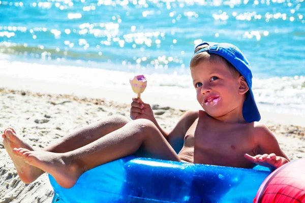 Niño con helado en la playa sentado en tubo de agua — Foto de Stock