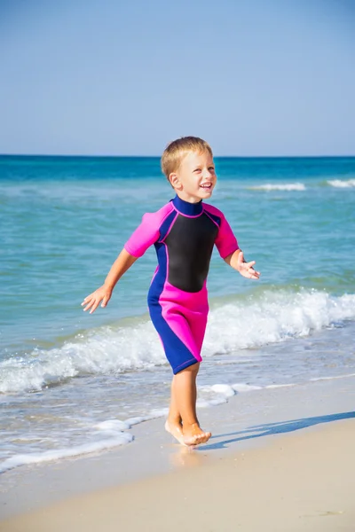 Kid i sin dykardräkt lämnar vattnet på stranden — Stockfoto