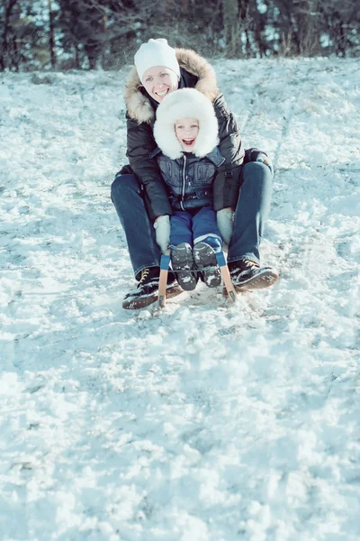 Jovem bela mãe e seu pequeno filho no trenó — Fotografia de Stock
