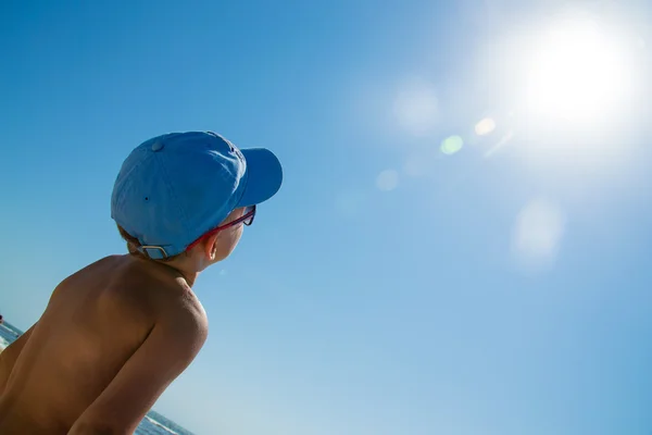 Gyerek kék sapka és napszemüveg keresi a nap a tenger közelében — Stock Fotó