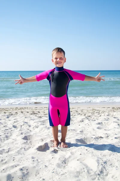 Menino pequeno em seu terno de mergulho sorrindo na praia — Fotografia de Stock