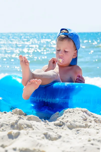 Niño con helado en la playa sentado en tubo de agua — Foto de Stock