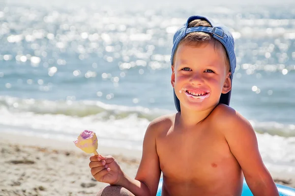 Bambino con gelato sulla spiaggia seduto in tubo dell'acqua — Foto Stock