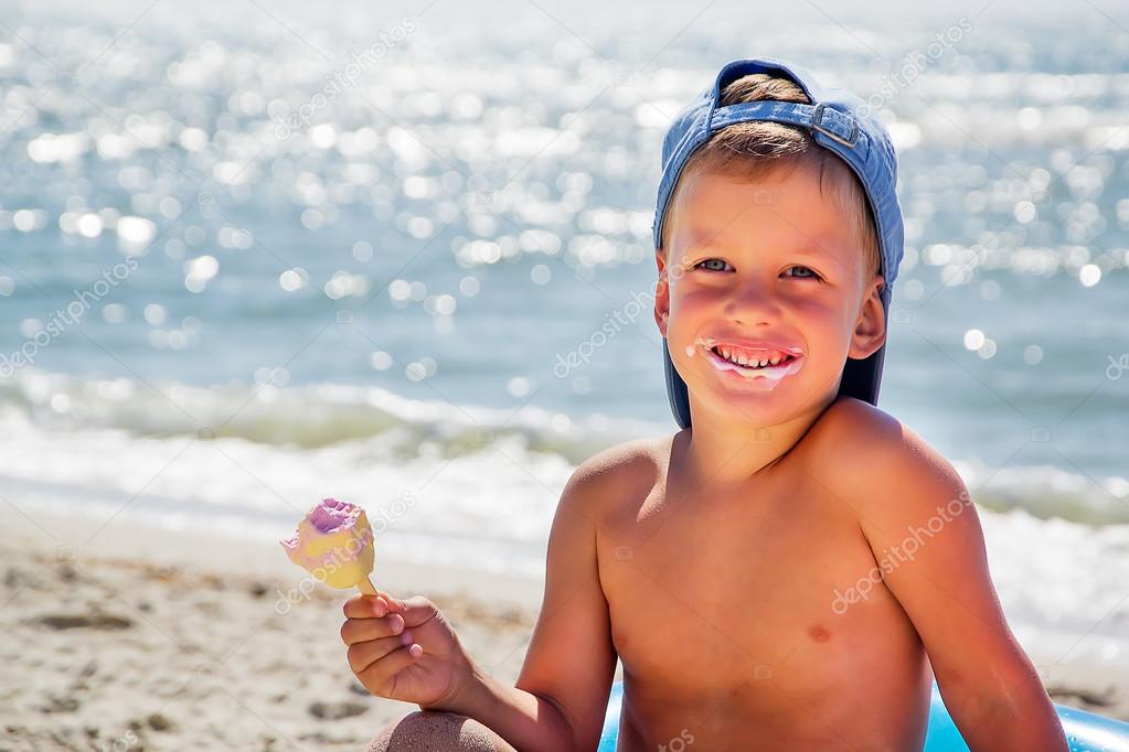 kid with ice cream on beach sitting in water tube