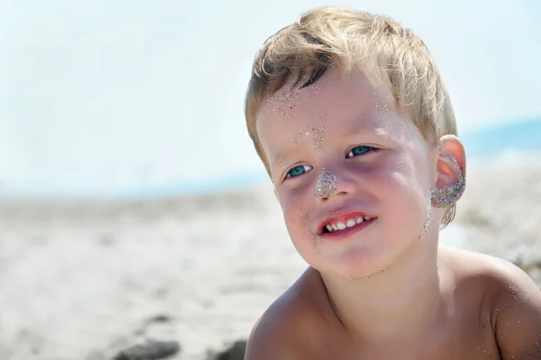 Portrait of three years boy on beach, face in sand — Stock Photo, Image