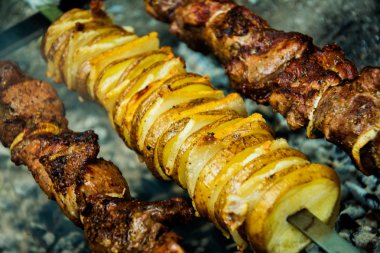 Meat and potatoes on skewers, cooked hot coals clipart
