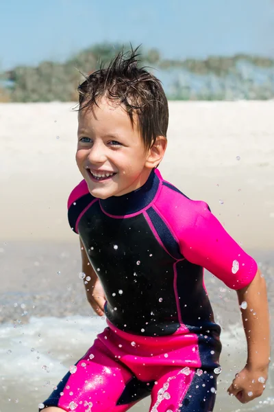 Menino pequeno em seu terno de mergulho sorrindo na praia — Fotografia de Stock