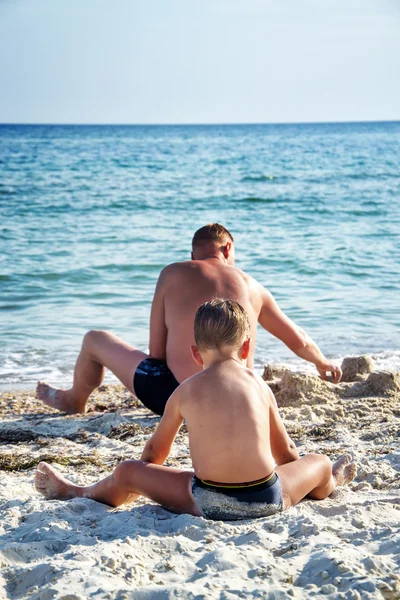 Far och hans son spelar i sand på stranden — Stockfoto