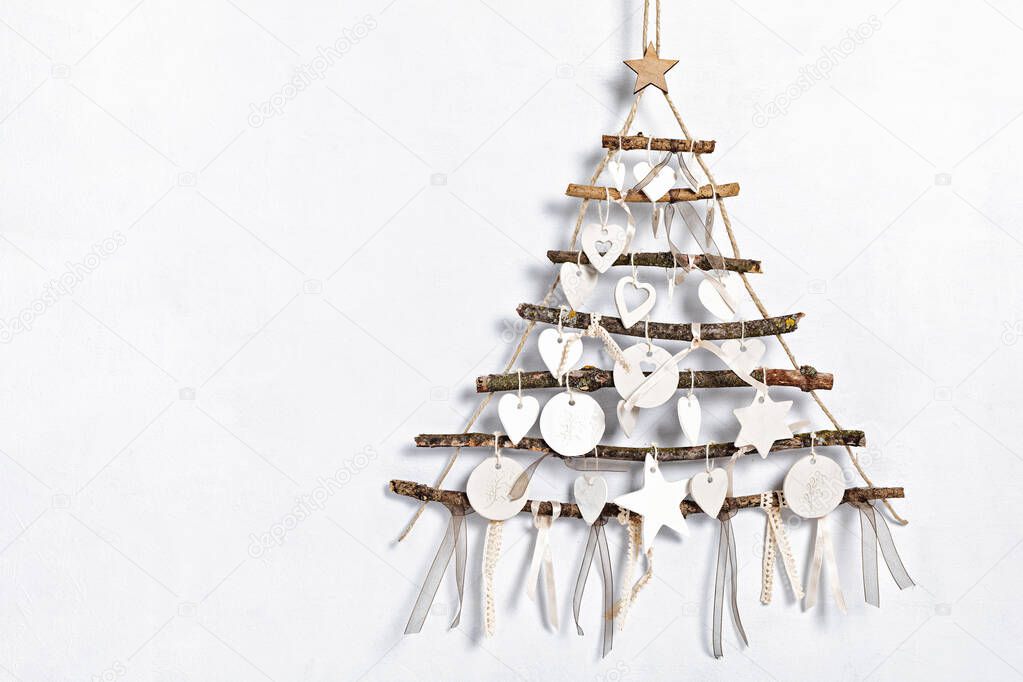 Zero waste christmas with alternative handmade xmas tree hanging over light wall and clay ornaments