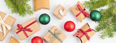 Kağıt çeşitleri ile pankart paketlenmiş Noel hediyeleri, ve beyaz arka planda çam dalları ile kırmızı ve yeşil mücevherler, düz, üst görünüm